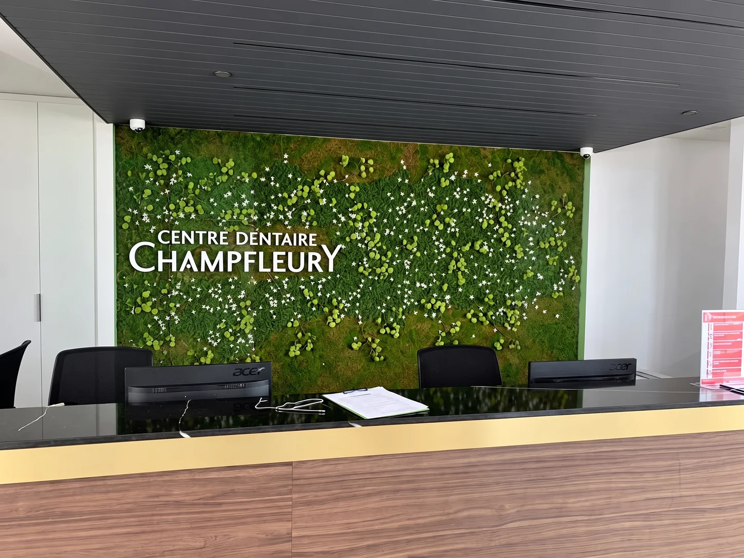 Comptoir de réception du Centre dentaire Champfleury devant le mur végétal.