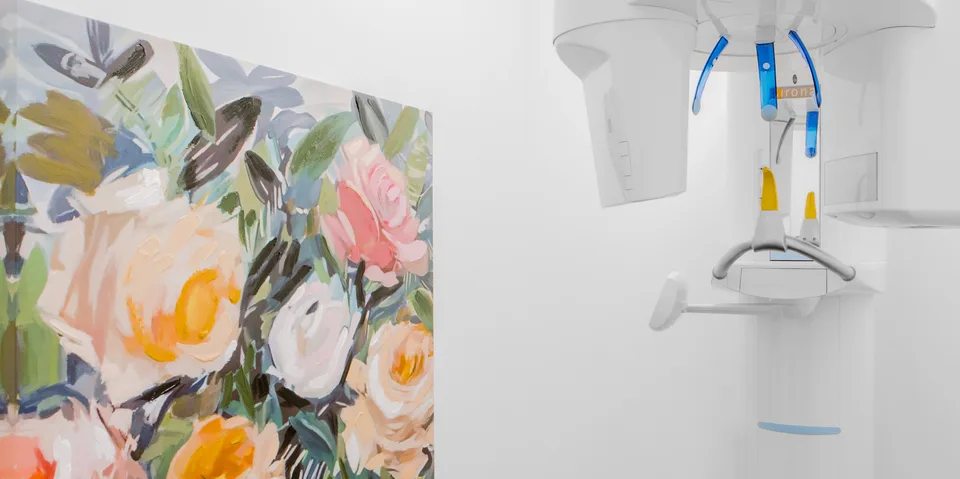Appareil de radiologie dentaire dans une pièce blanche avec un tableau floral.